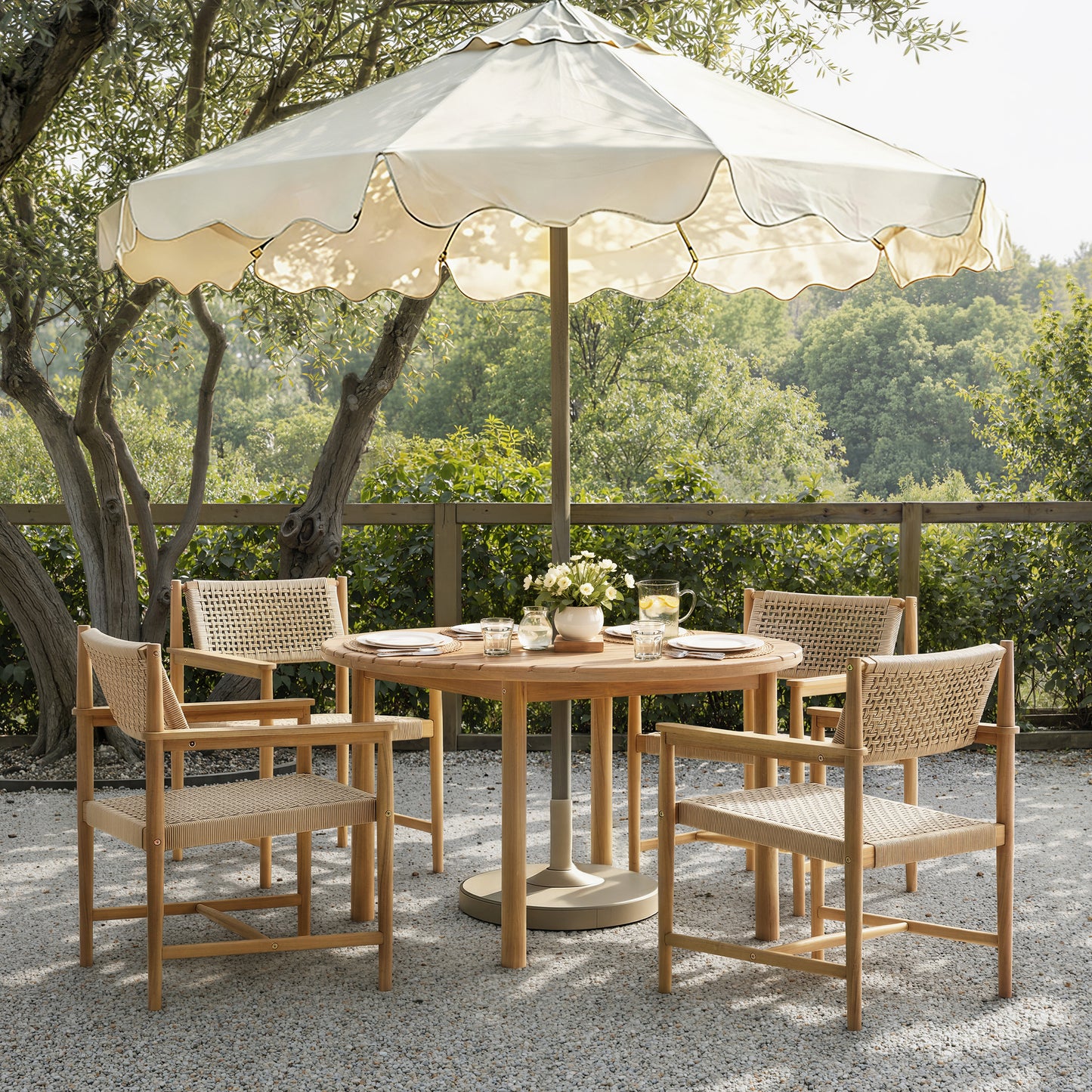 Outdoor dining set with table and chairs under a large umbrella on a gravel patio.