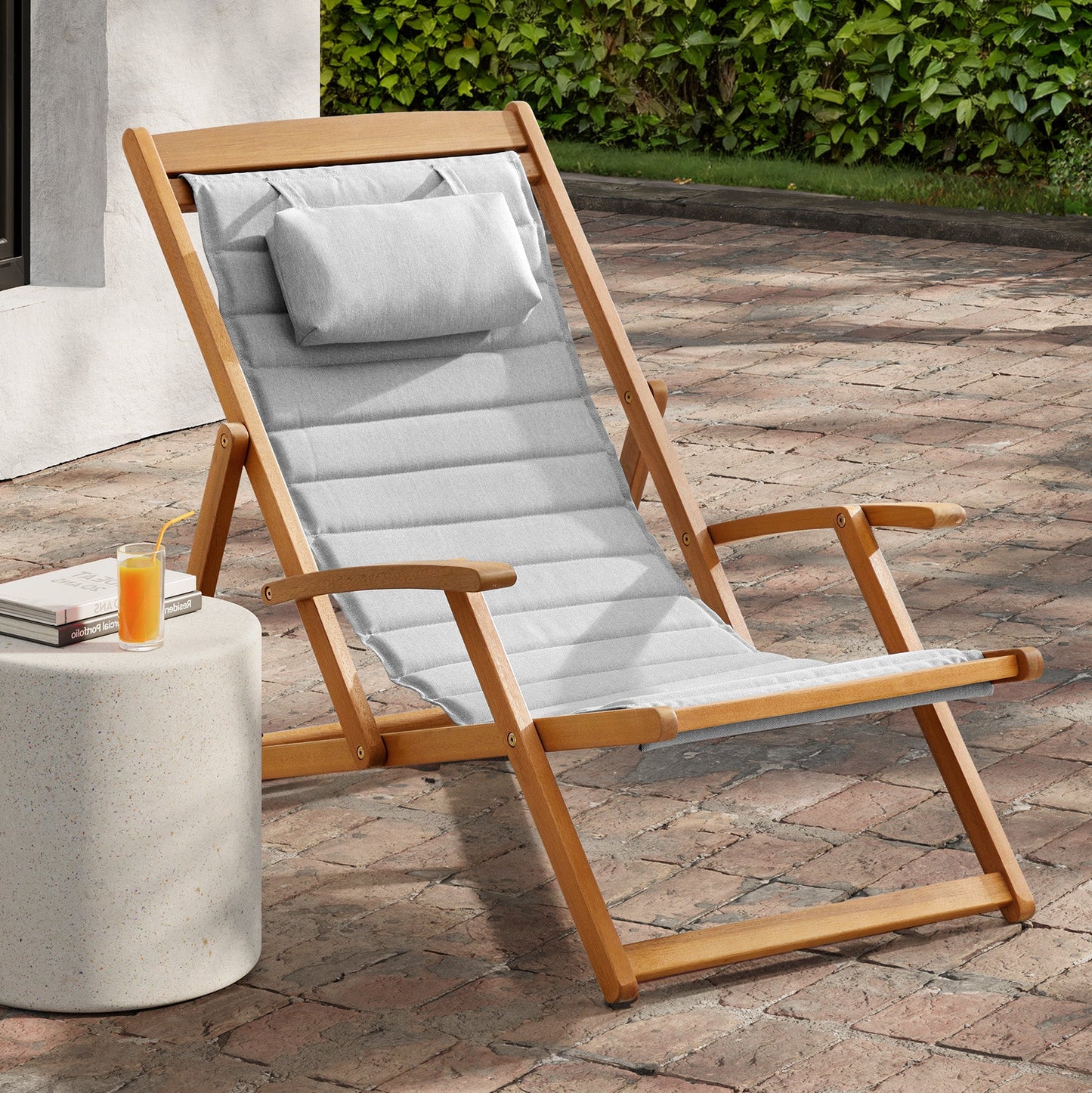 Clara deck chair with grey cushions next to a side table on a patio